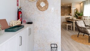 Een moderne keuken met witte kastjes, een brandblusser en een eethoek met een tafel en stoelen.