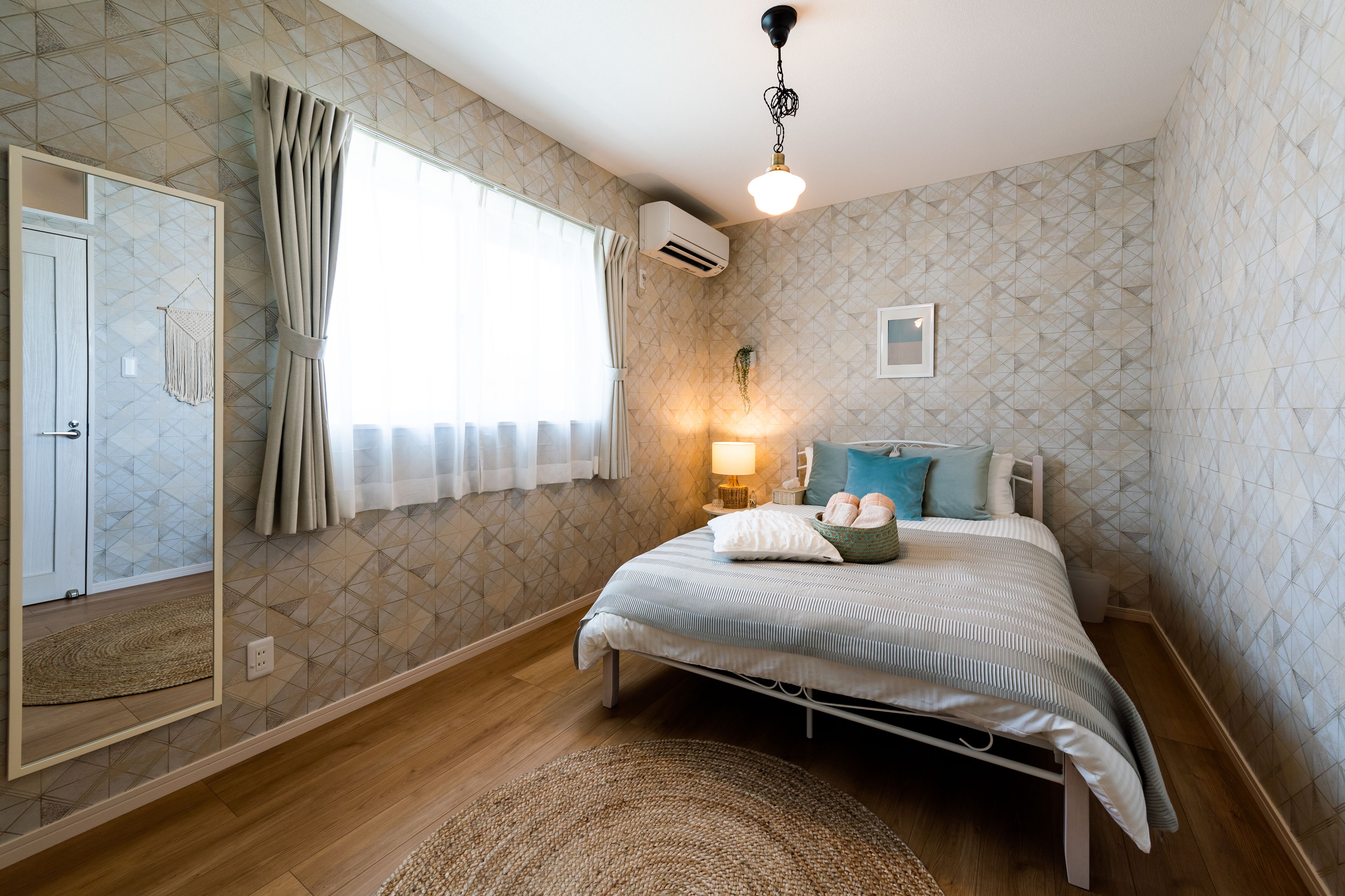 Un dormitorio con cama, mesita de noche, lámpara y ventana con cortinas.