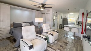 A modern living room with a sofa, two white armchairs, a coffee table, and a ceiling fan. - Kanda Zen Apt 3 - pool & walk to the beach! (Pompano Beach)