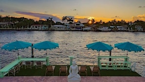 A waterfront view with a Buddha statue, lounge chairs, and umbrellas. - Kanda Zen Apt 3 - pool & walk to the beach! (Pompano Beach)