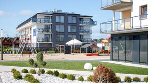 A modern apartment building with multiple balconies, a playground, and a well-maintained garden area. - Blu Apartments (Sarbinowo)