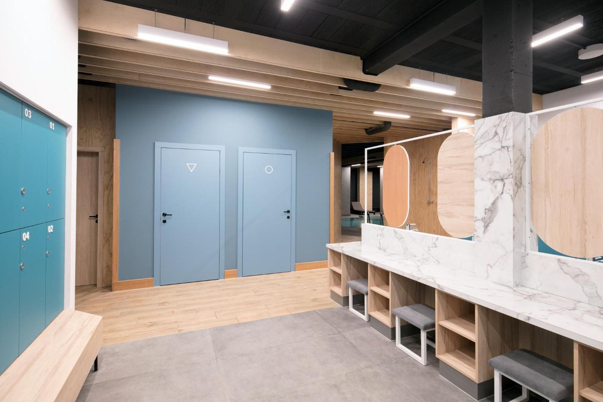 A modern bathroom with blue lockers, a marble vanity, and wooden accents.