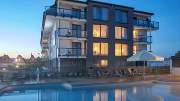 A multi-story hotel with balconies, a swimming pool, and lounge chairs.