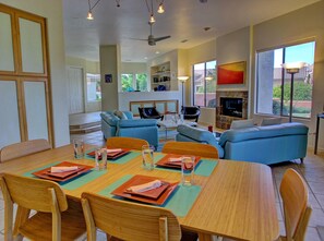 Un grand espace de vie comprenant une table à manger pour quatre personnes, un canapé et un téléviseur.