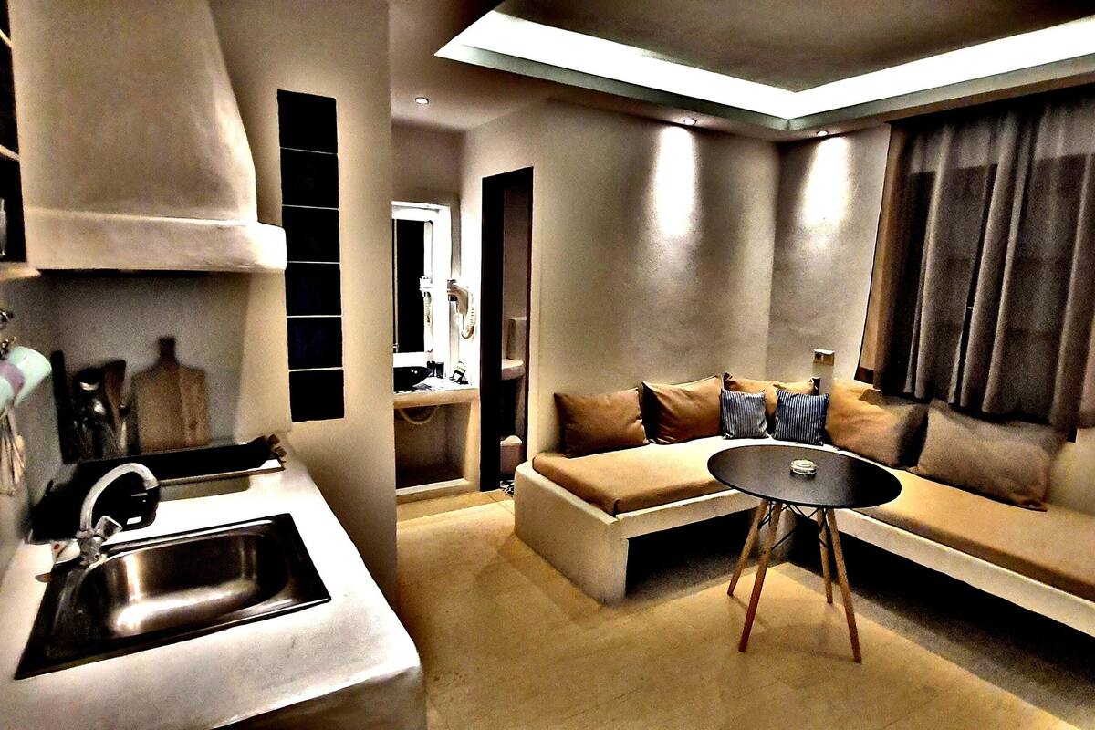 Un espacio habitable pequeño con kitchenette, un sofá y una mesa.