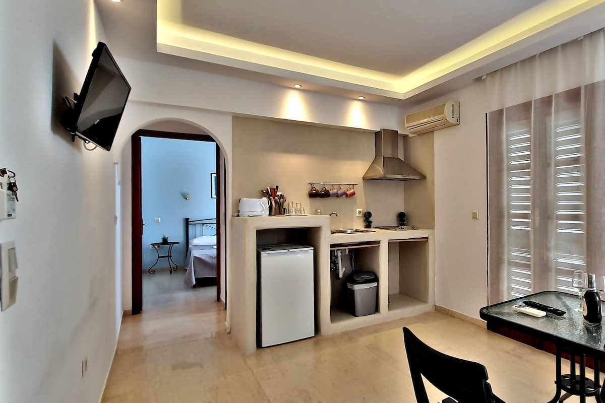 Un espacio habitable compacto con kitchenette, comedor y televisor montado en la pared.
