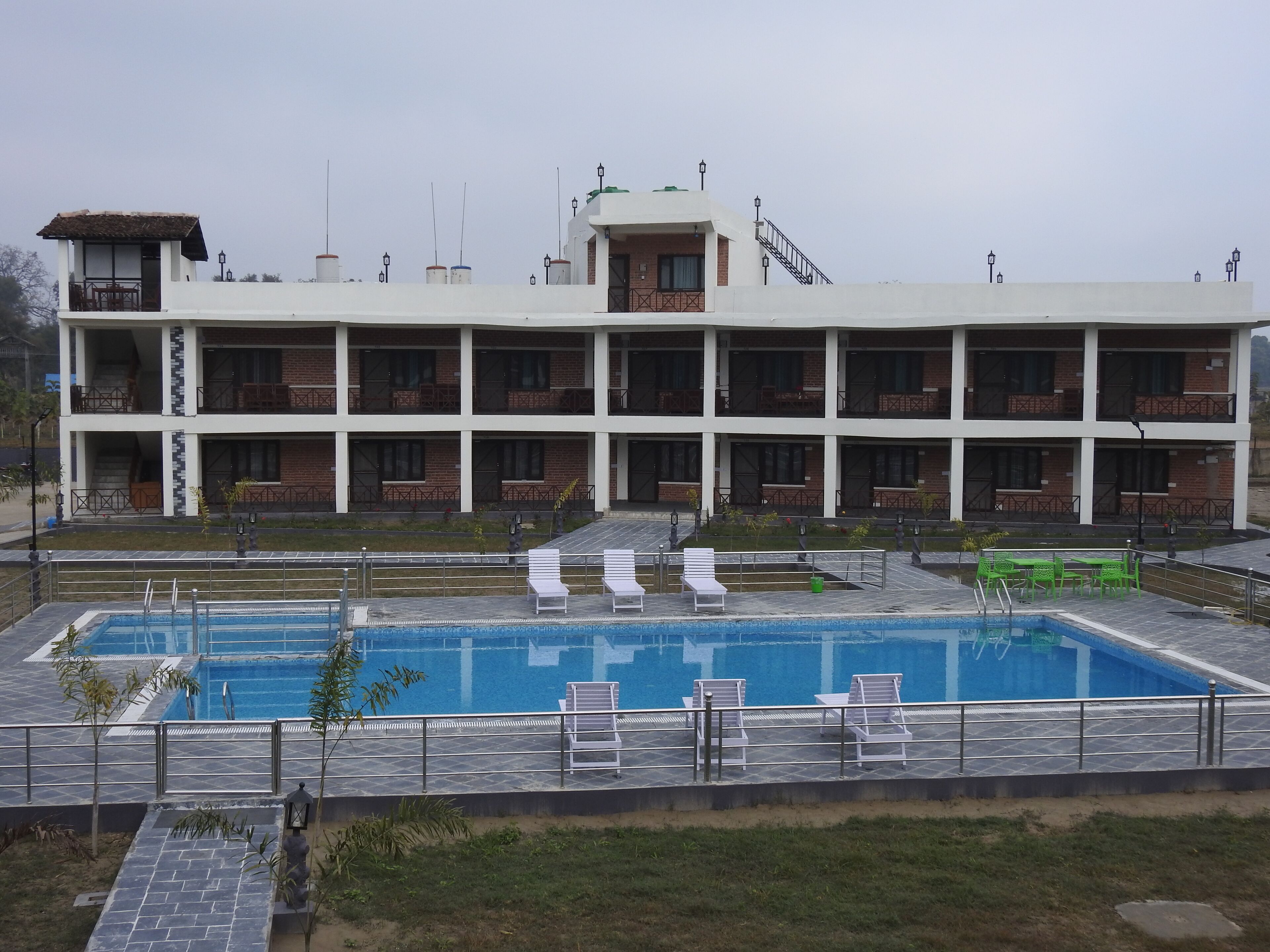 A multi-story hotel with a swimming pool, outdoor seating, and a well-maintained garden area.