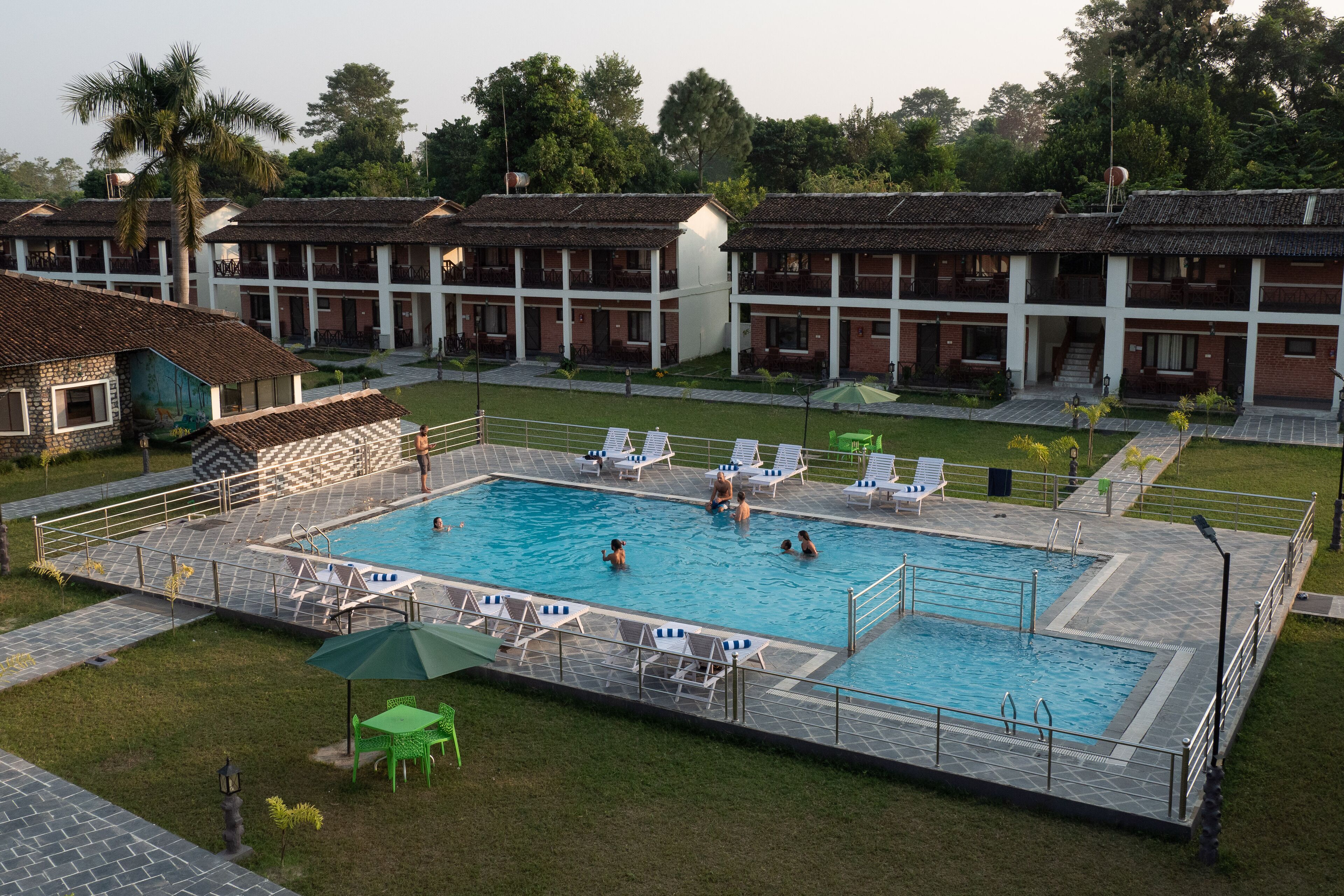 A swimming pool surrounded by lounge chairs and a small table, with a building in the background.