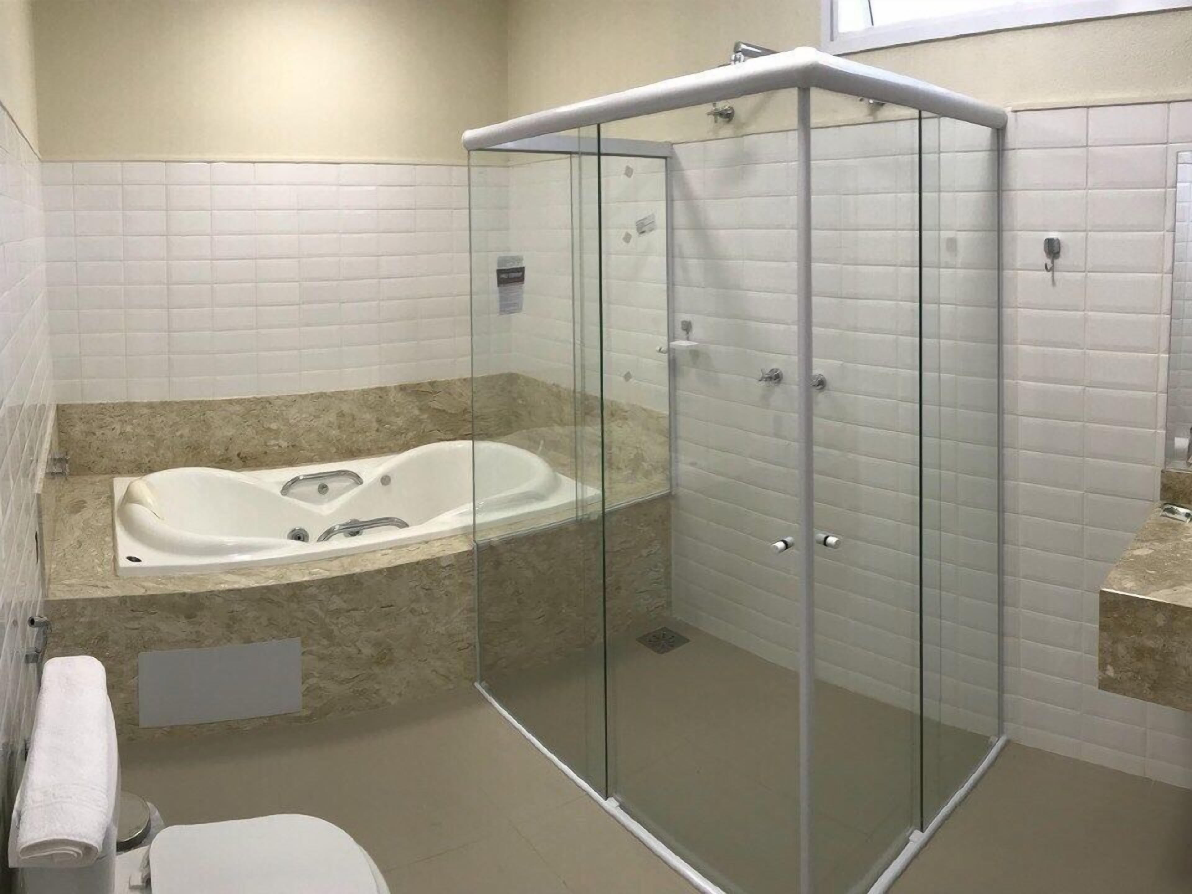 Un baño moderno con ducha de vidrio, una bañera independiente y un inodoro.