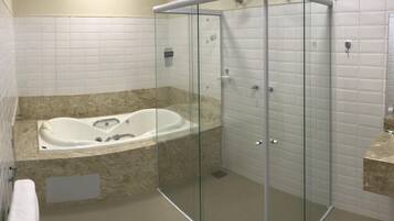 Un baño moderno con ducha de vidrio, una bañera independiente y un inodoro.