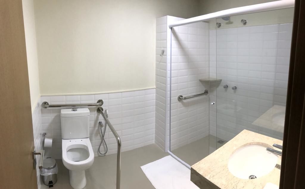 A bathroom with a toilet, a glass-enclosed shower, and a sink with a marble countertop.