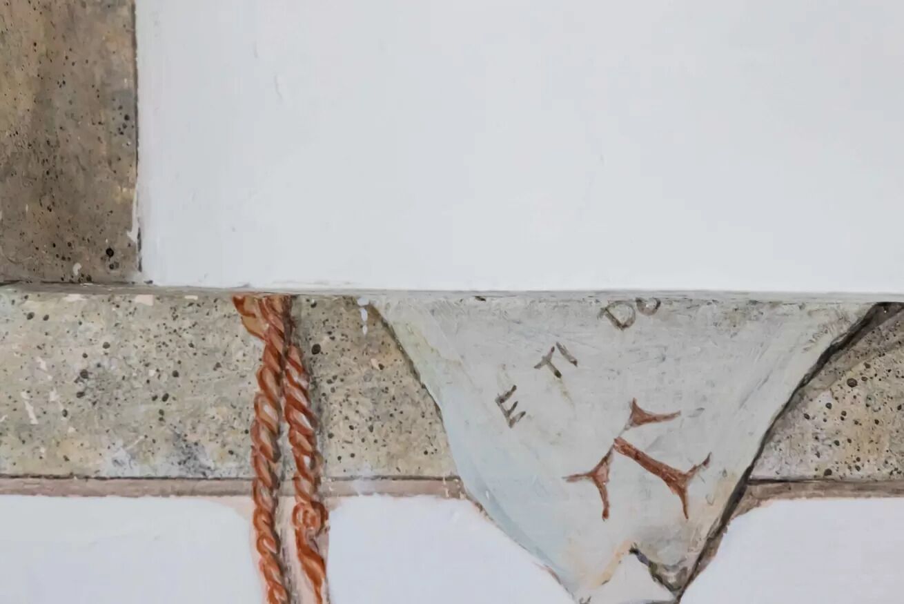 A corner of a building with a concrete wall and a metal chain.