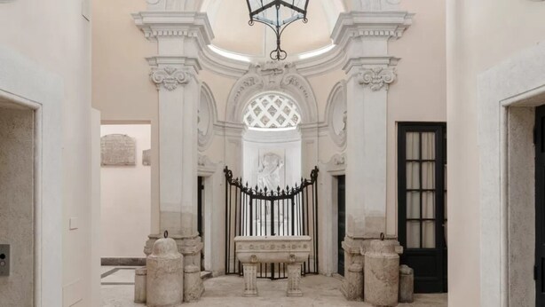 A grand hallway with ornate columns, a central statue, and a black iron gate. - A World Aparts - Torre Argentina Apartments (Rome)