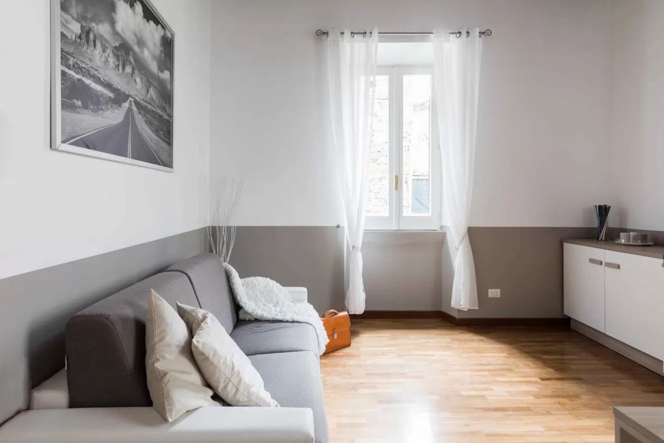 Una sala de estar moderna con un sofá gris, un cojín blanco y un cuadro en la pared.
