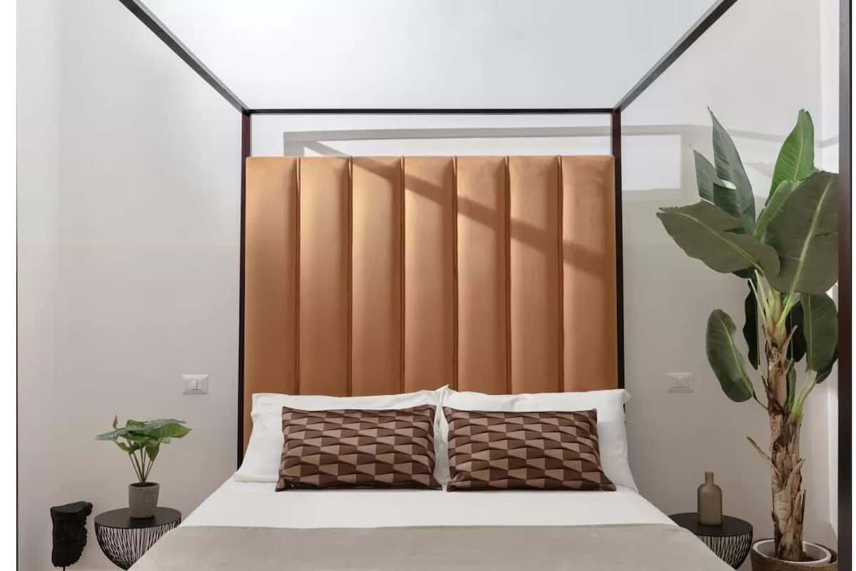 Une chambre à coucher moderne avec un lit, deux oreillers, une plante sur la table de chevet et une commode.