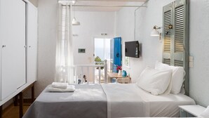 A bedroom with two beds, a TV, and a balcony with a view. - Ferma Hill Apartments (Ierapetra)