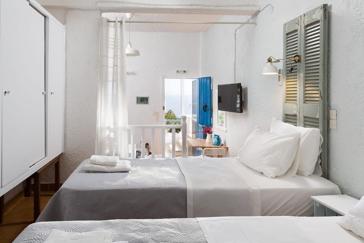 Ein Schlafzimmer mit zwei Betten, einem Fernseher und einem Balkon mit Blick.