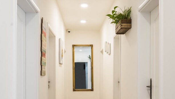 A hallway with wooden flooring, white walls, and doors on both sides. - Apart-Hostel ZERO (Bratislava)
