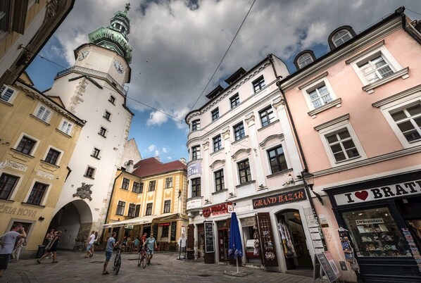 Eine Straße mit historischen Gebäuden, einem Glockenturm und verschiedenen Geschäften.