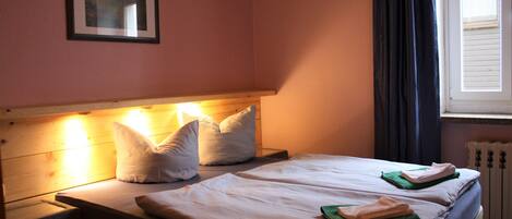 A double bed with two pillows, a bedside table, and a framed picture on the wall.