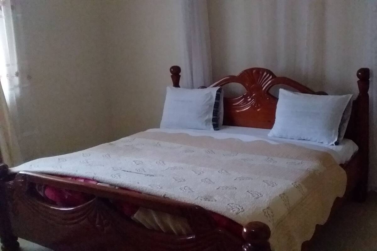 A bed with a wooden headboard, white bedding, and two pillows.