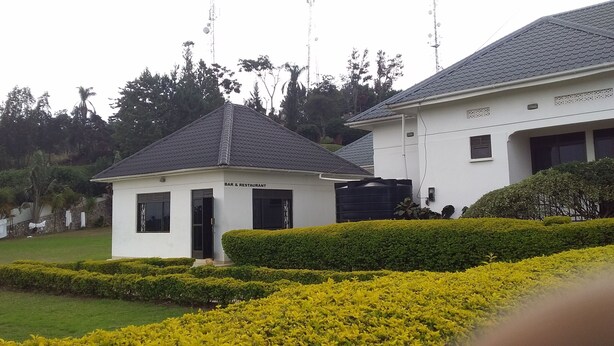 A white building with a small attached structure labeled "BAR & RESTAURANT". - Trust White Hotel (Bushenyi)