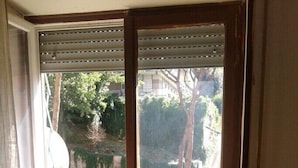 A room with a window overlooking a street, a bookshelf, and a small trash bin. - Bright apartment 200 meters from the Sistine Chapel (Roma)
