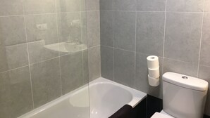 Une salle de bain comprenant une baignoire, des toilettes et un espace douche.