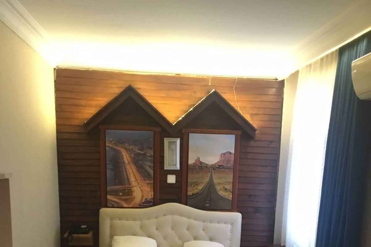 A hotel room with a large bed, a small table, and two paintings on the wall.