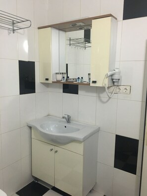 Un baño con un lavamanos blanco, un espejo y un secador de pelo enchufado.