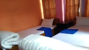 A hotel room with two single beds, a wooden nightstand, and a white blanket on the left bed. - Big Bell Guest House (Bhaktapur)