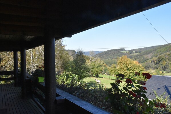 Eine Holzterrasse mit Blick auf eine grüne Landschaft und Hügel.