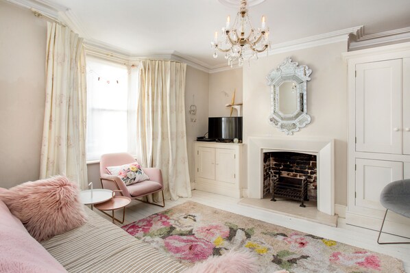 A living room with a sofa, armchair, fireplace, and a chandelier.