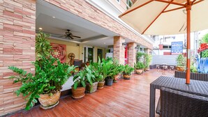 An outdoor patio area with potted plants, wicker furniture, and a ceiling fan. - Salin Home Hotel Ramkhamhaeng (Bangkok)