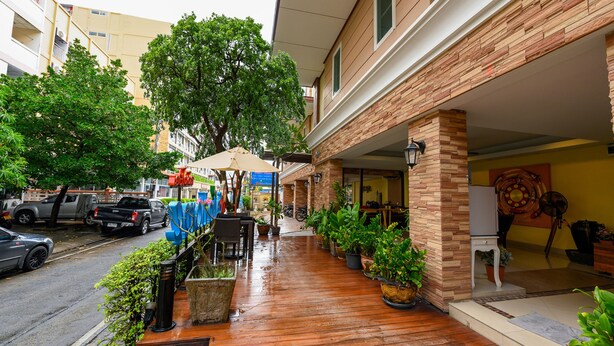 A covered outdoor area with wooden flooring, potted plants, and a seating arrangement. - Salin Home Hotel Ramkhamhaeng (Bangkok)