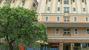 A multi-story hotel with a beige facade, a prominent 'Sarin Home' sign, and a tree in the foreground. - Salin Home Hotel Ramkhamhaeng (Bangkok)