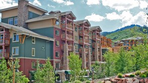 A multi-story hotel with balconies, a stone chimney, and a view of a mountainous landscape. - Coming soon! Coming soon! Coming soon! Coming soon! Coming soon! (Park City)