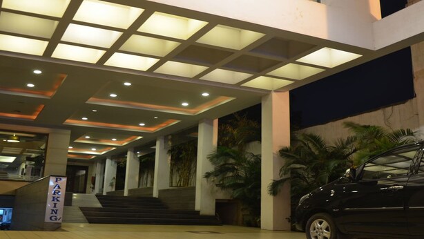 Un edificio moderno con techo de vidrio, un letrero de estacionamiento y una escalera que sube a un nivel superior.