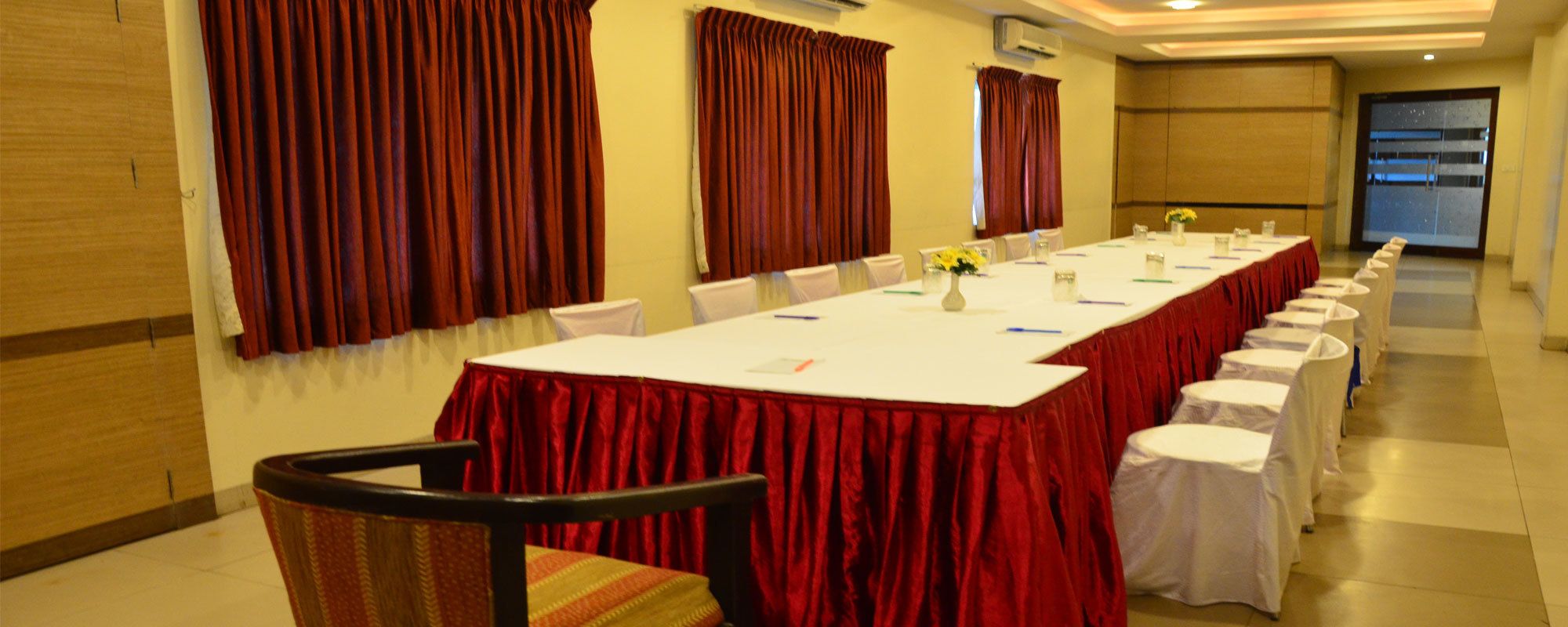 A conference room with a long table, chairs, and red curtains.