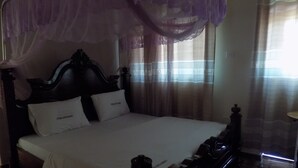 Uma cama com dossel, cabeceira e duas almofadas.