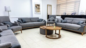 A modern living room with grey sofas, a round wooden coffee table, and a floor lamp. - New Gate Hostel (Jerusalem)