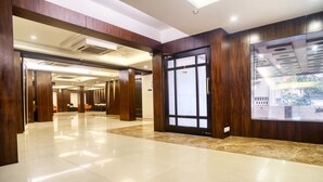 A spacious lobby with a polished tile floor, wooden paneling, and a large glass door with a 'CLOSE' sign. - Roland Hotel (Kolkata)