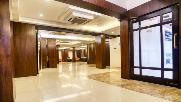 A hotel lobby with a polished tile floor, wooden paneling, and a closed door with a 'CLOSE' sign. - Roland Hotel (Kolkata)
