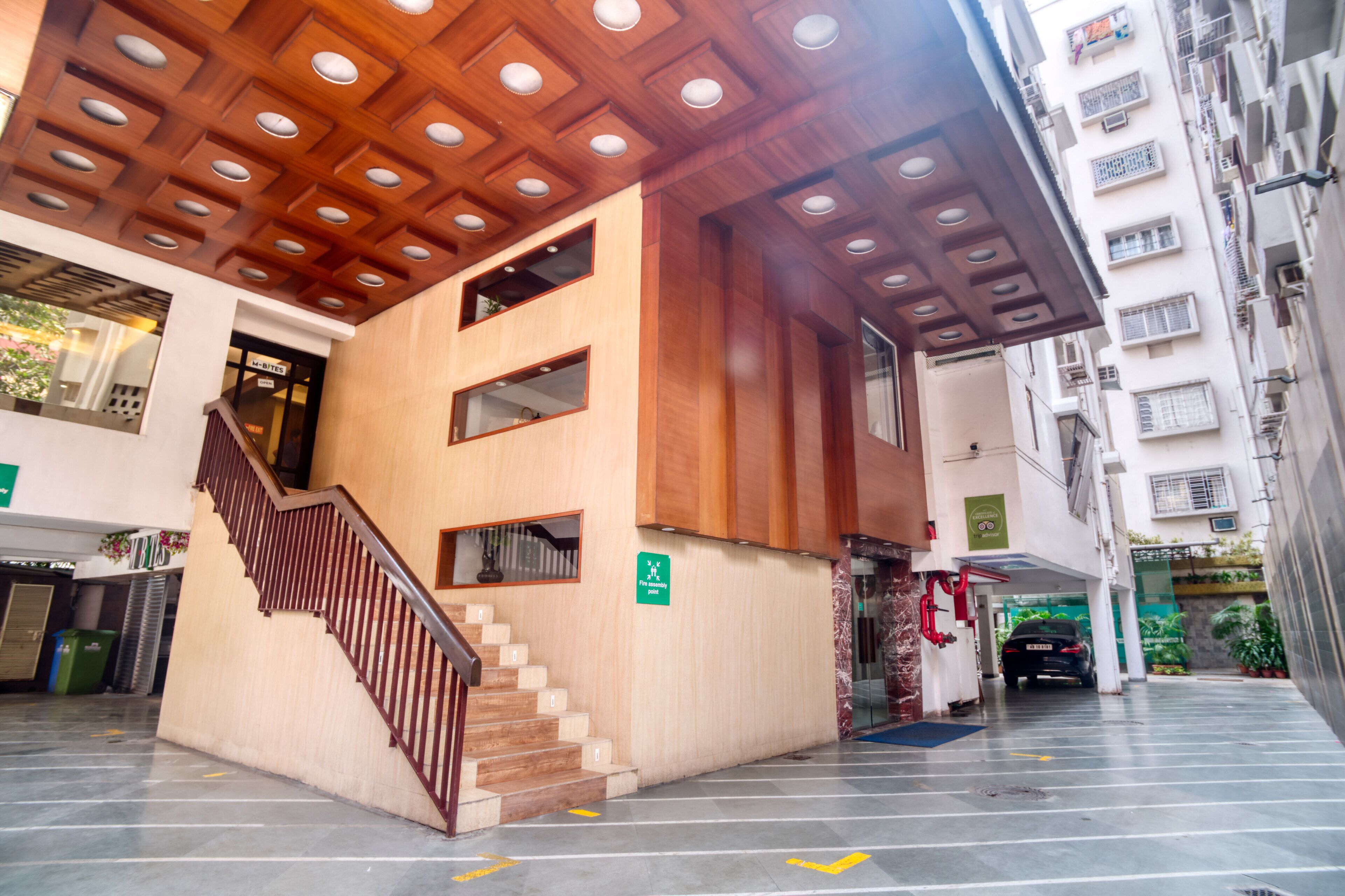 A modern building with a wooden ceiling, a staircase, and a car parked outside.