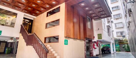 A modern building with a wooden ceiling, a staircase, and a car parked outside.