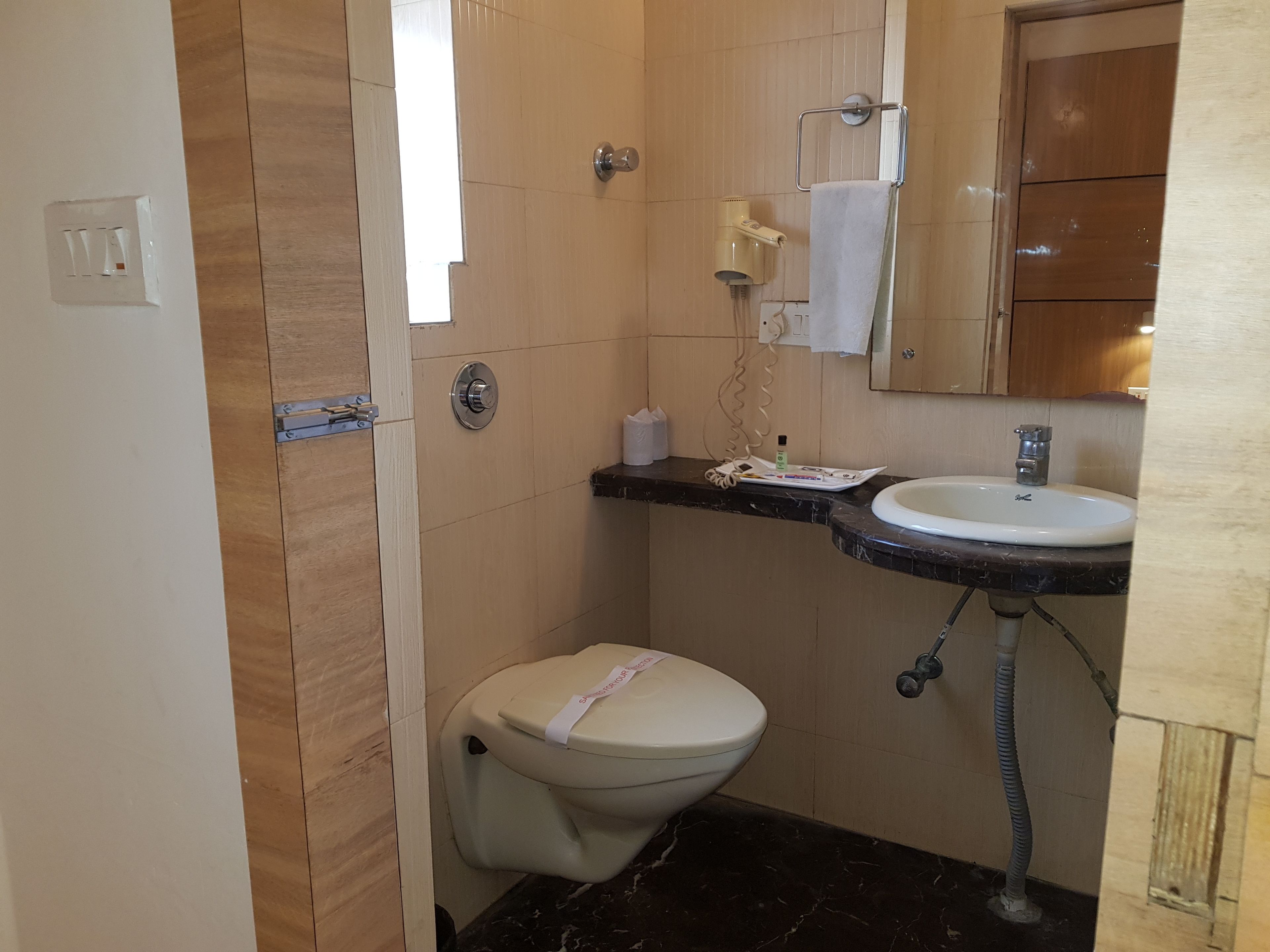 A compact bathroom with a toilet, sink, and mirror.