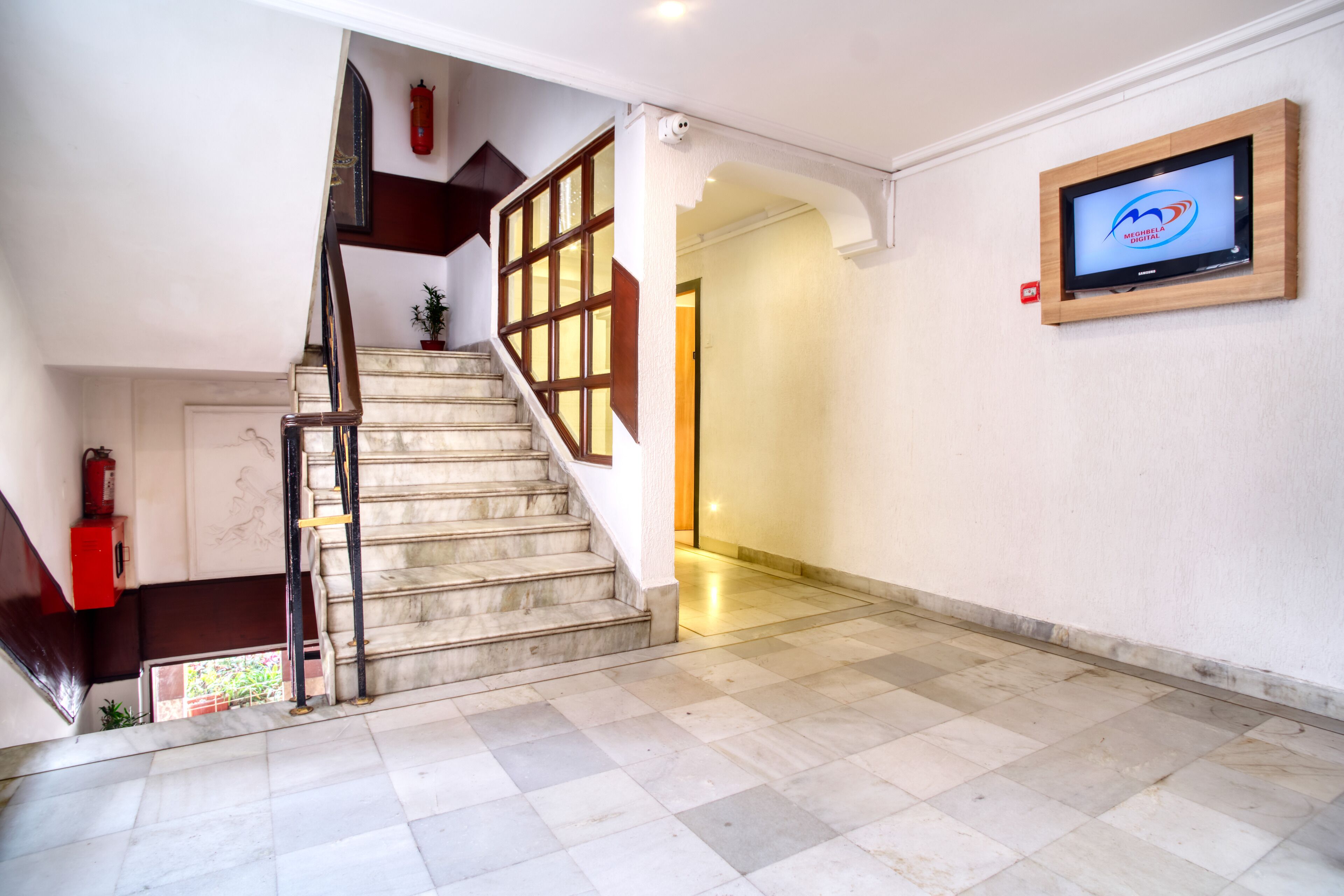 A staircase with a wooden handrail leading to a landing. A fire extinguisher is mounted on the wall beside the stairs.