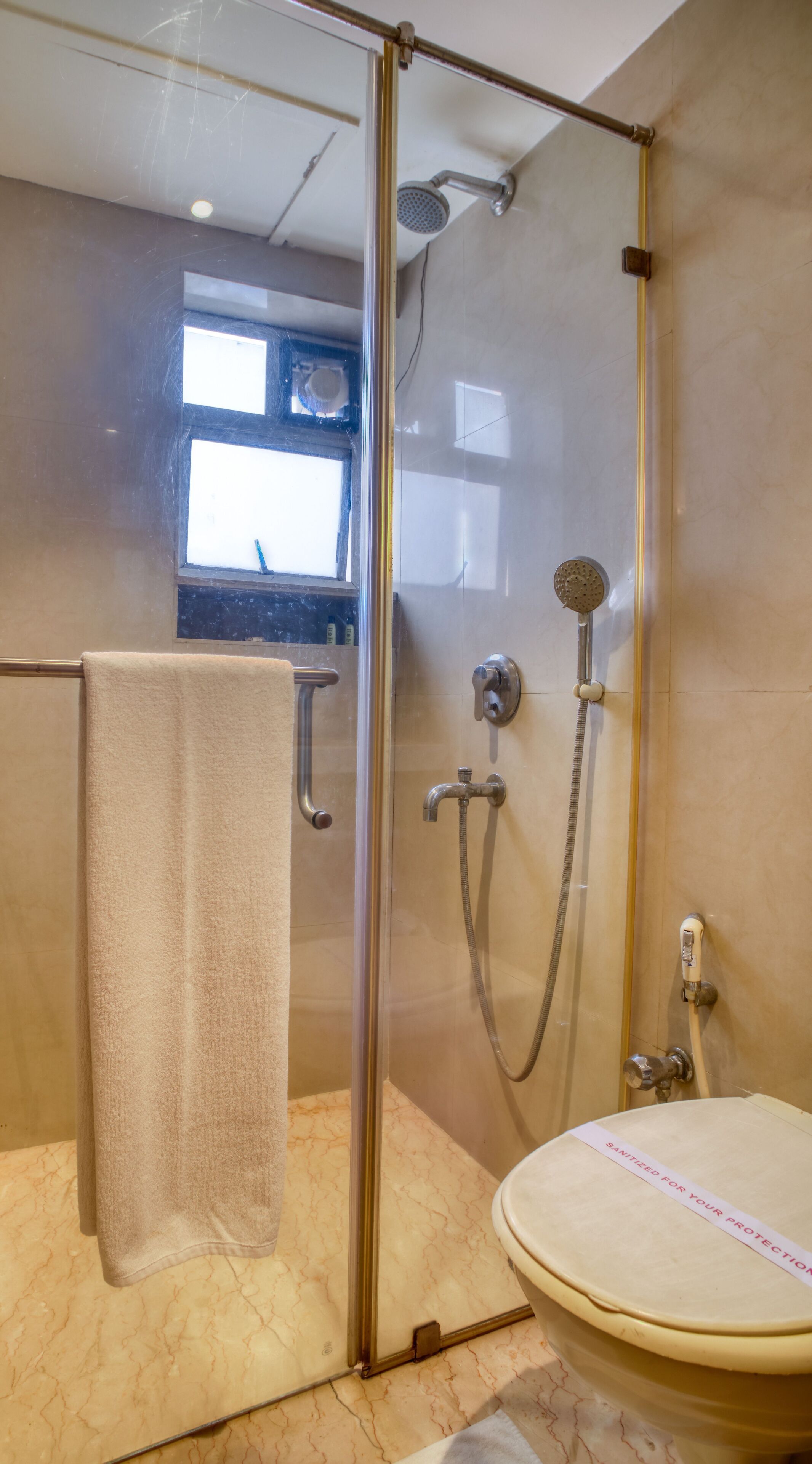 A glass-enclosed shower with a handheld showerhead and a wall-mounted faucet.