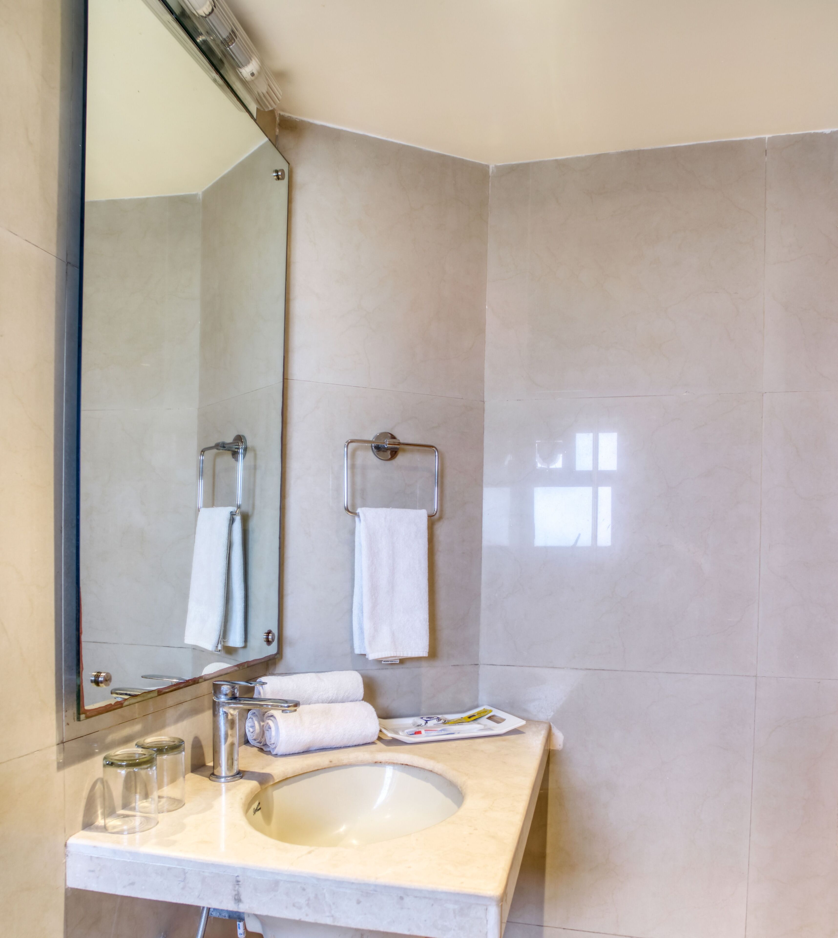 A bathroom with a sink, mirror, towel rack, and a tiled wall.