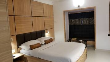 Un dormitorio moderno con cabecera de madera, cama con ropa blanca, mesita de noche y ventilador de techo.